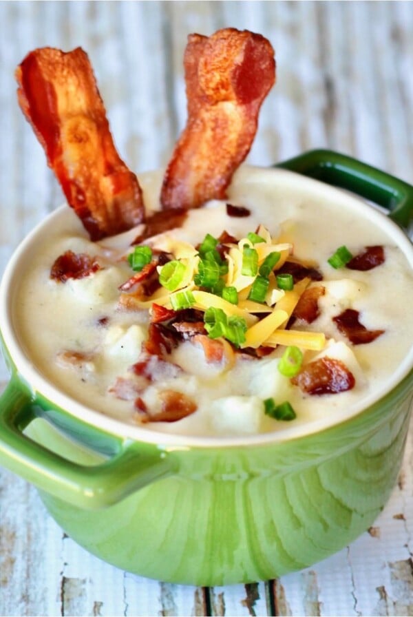 Small green bowl of potato soup with bacon.