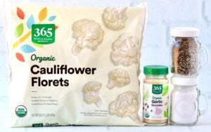 Bag of frozen cauliflower on a countertop with garlic powder, salt, and pepper.