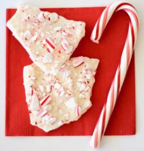 Two pieces of peppermint bark on napkin with candy cane.