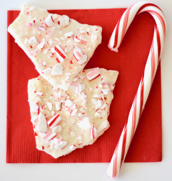 Two pieces of peppermint bark on napkin with candy cane.