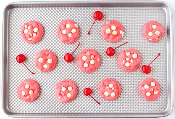 Baked cherry cookies on cookie sheet with cherries.