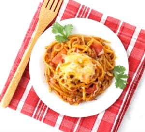 Taco spaghetti on a small plate with a wooden fork.