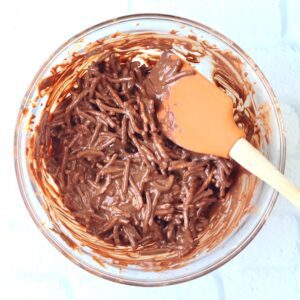 Spatula stirring chow mein noodles with chocolate and peanut butter.