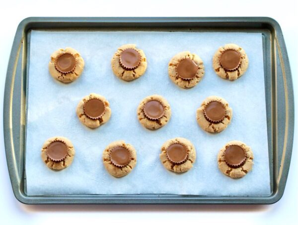 Reese Peanut Butter Cup Cookies arranged on a parchment covered cookie sheet.