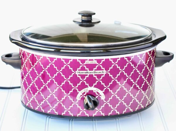 Pink and white slow cooker with a lid.