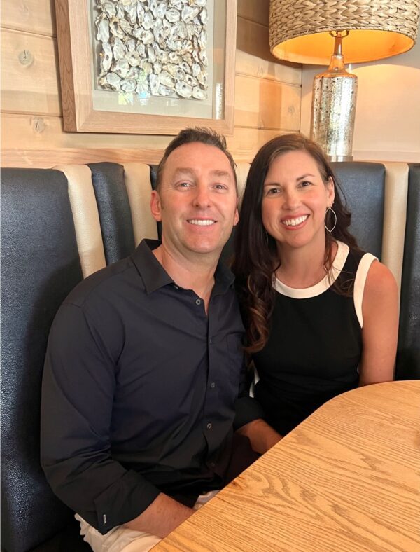 My husband and I smiling while sitting in a restaurant booth.