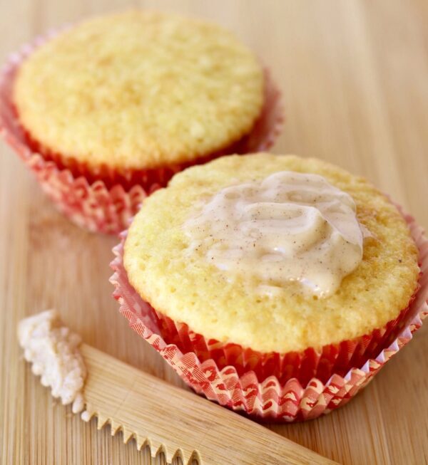 Two cornbread muffins, one of which is topped with cinnamon honey butter.
