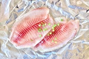 Seasoned tilapia on a sheet of foil.