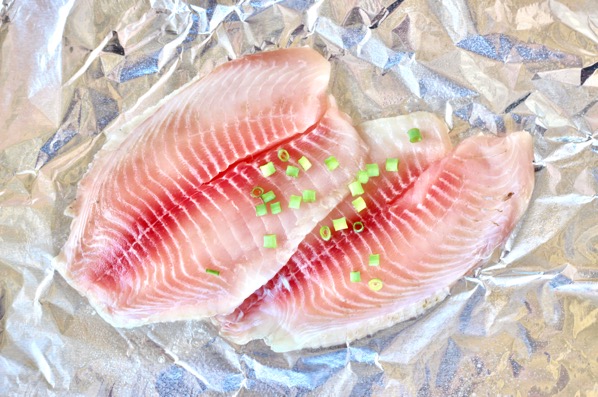 Seasoned tilapia on a sheet of foil.
