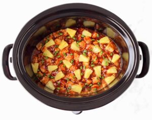 Sweet and sour pork with pineapple chunks in a Crockpot.