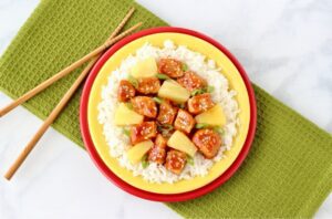Sweet and Sour Pork over rice on a plate.