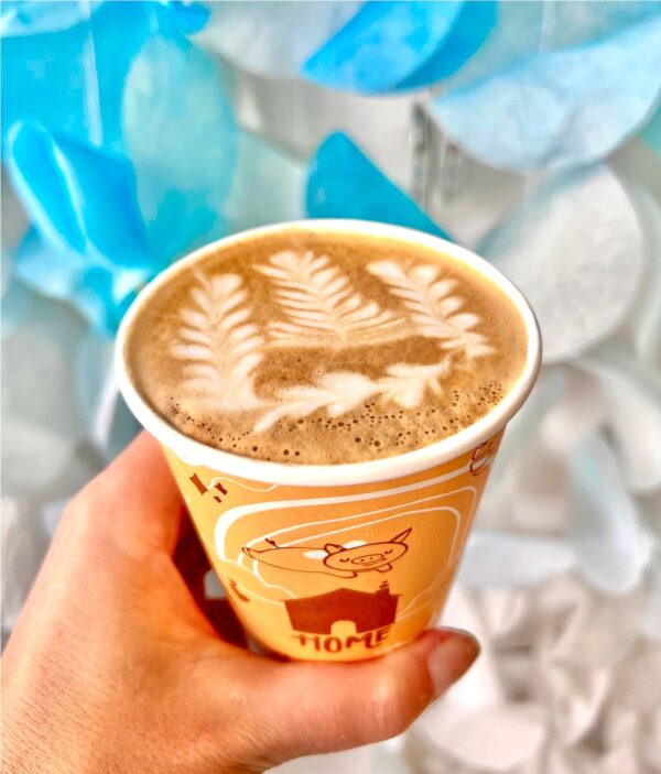 Hand holding latte with latte art.