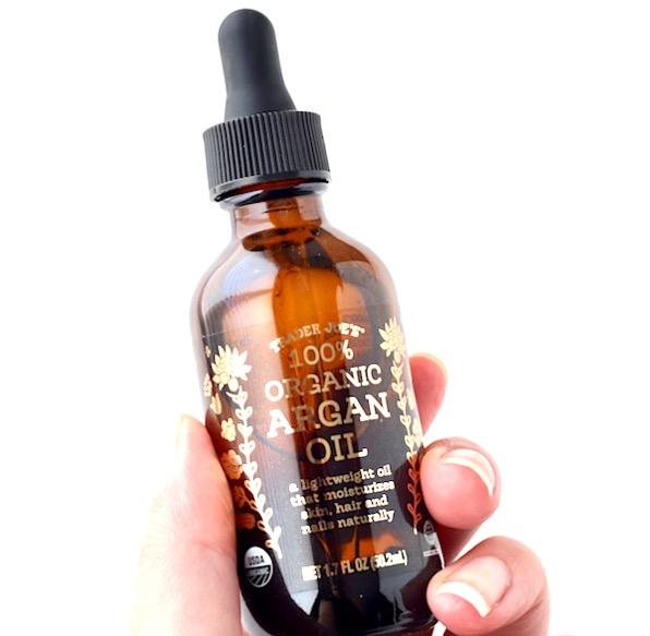 Person holding a container of argan oil.