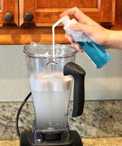 Person adding soap to a blender.