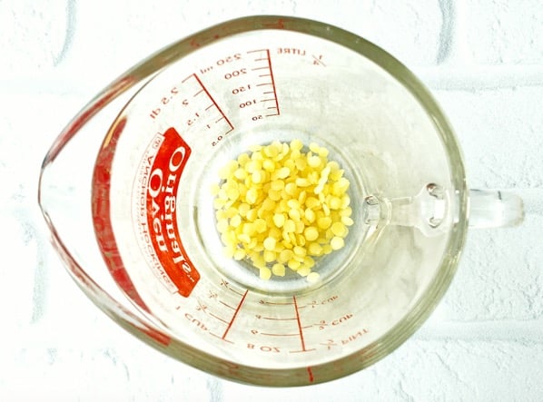 Beeswax pellets in a measuring cup.