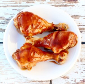 Cooked drumsticks on plate with barbecue sauce.