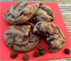 Dark chocolate fudge cookies on napkin with chocolate chips.