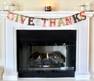 Give thanks banner hanging from fireplace mantle.