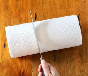 Paper towel roll getting cut with knife.