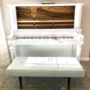White upright piano with piano bench.
