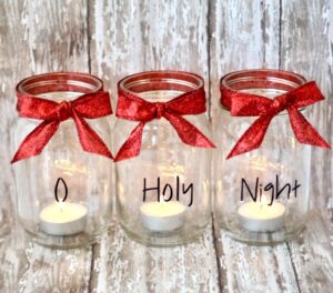 Three mason jars with red bows and tea light candles inside.