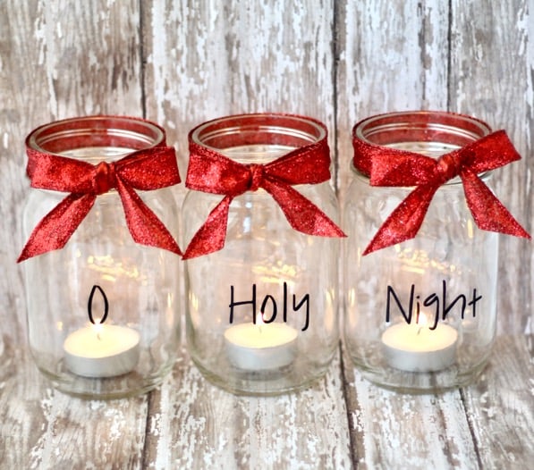 Three mason jars with red bows and tea light candles inside.