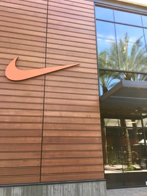 An orange Nike swoosh on the outside of a Nike retail store.