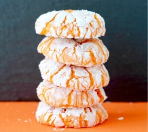 Stack of orange crinkle cookies coated in powdered sugar.