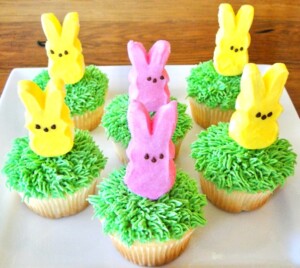 Baked cupcakes with Peeps standing on grass frosting.