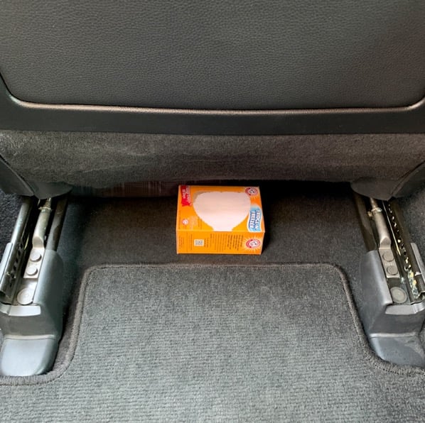 Baking soda box on floor under seat in car.