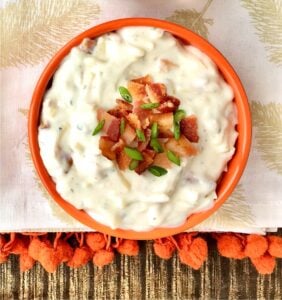 Ranch dip in bowl with bacon and chives on top.