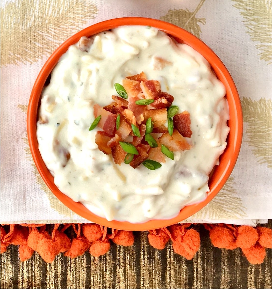 Ranch dip in bowl with bacon and chives on top.