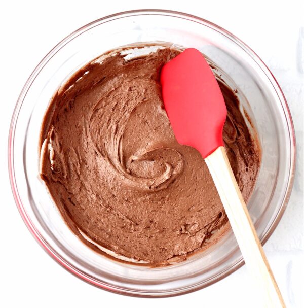 Chocolate cookie dough in bowl with spatula.