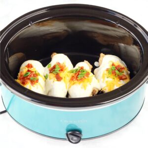 Four pieces of chicken in crockpot with ranch sauce, bacon, cheddar, and green onions on top.