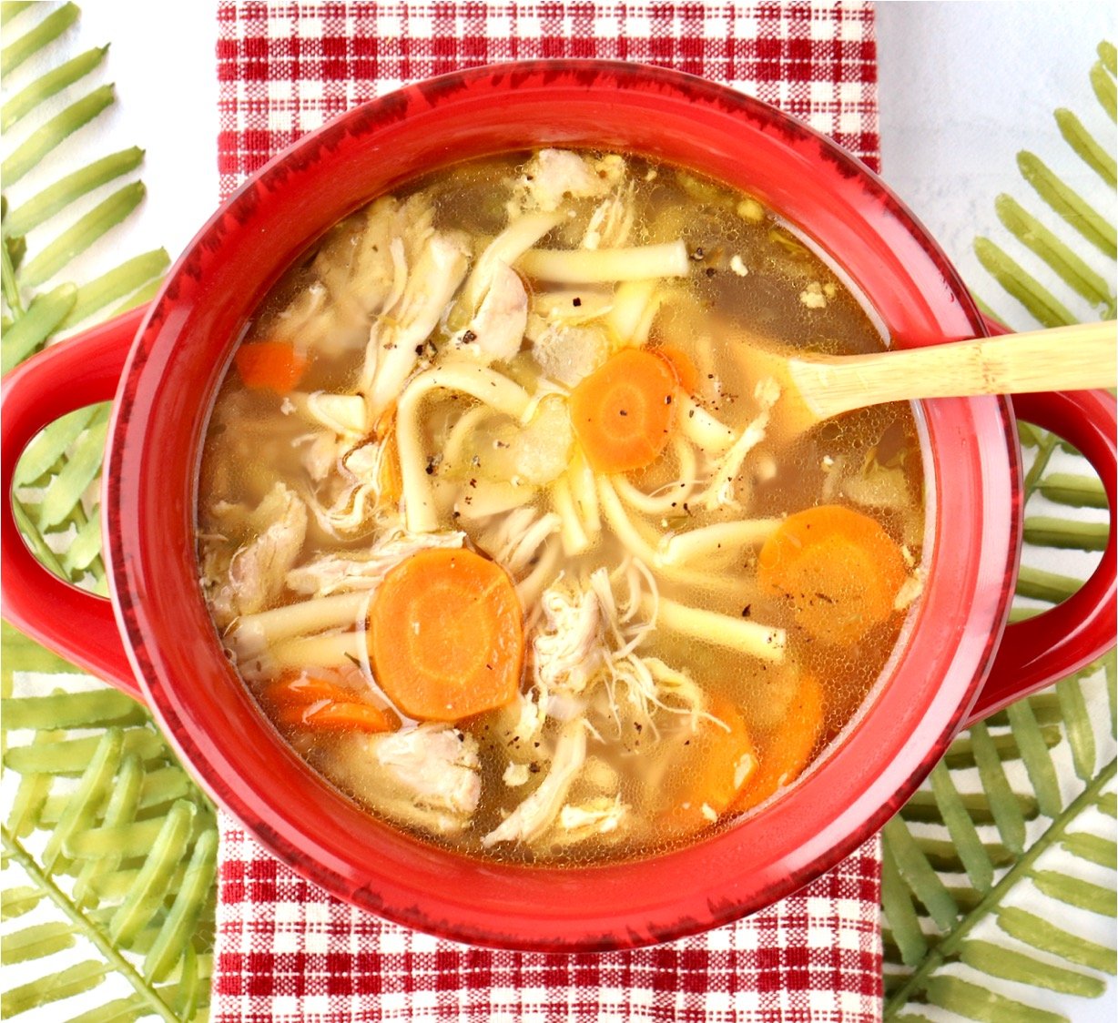 Chicken noodle soup in with carrots and rotisserie chicken in bowl.