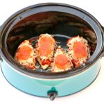 Four pieces of chicken in crockpot topped with pizza sauce, mozzarella cheese, and pepperoni slices.