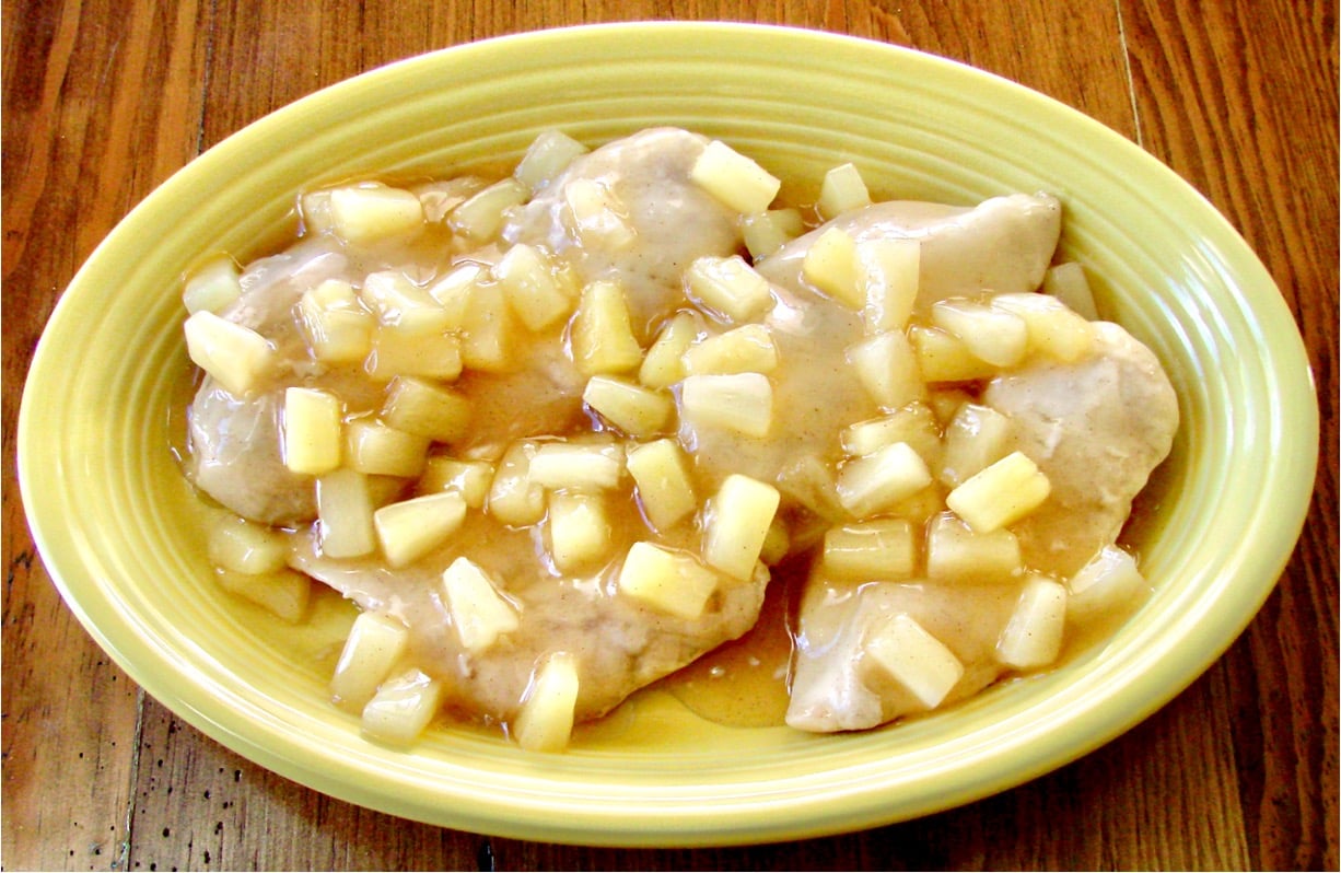 Baked chicken on platter with sweet and sour sauce and pineapple tidbits on top.