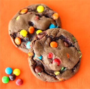 Two chocolate cake mix cookies with M&M's on napkin.