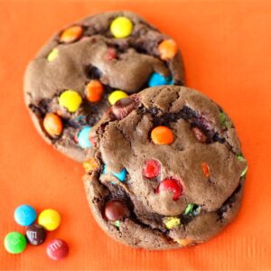 Two chocolate cake mix cookies with M&M's on napkin.