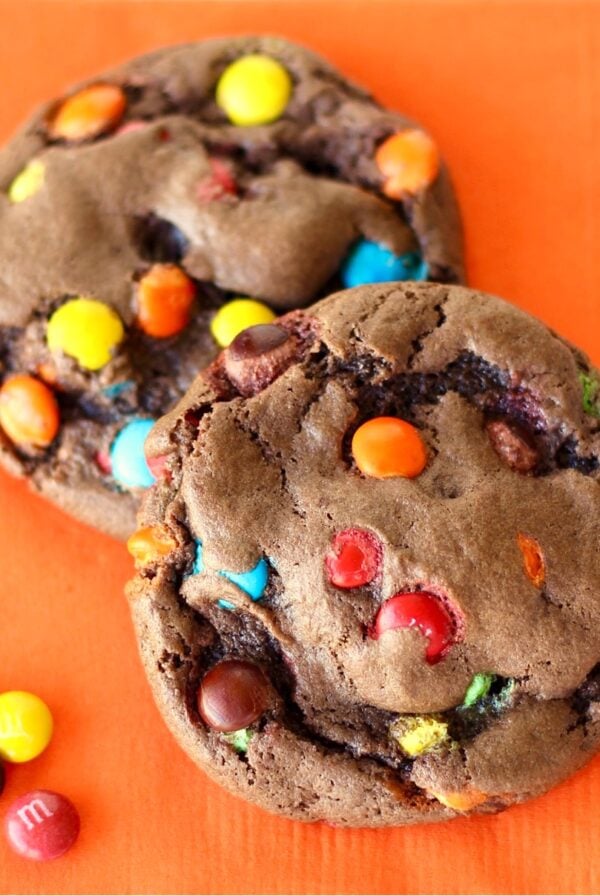 Two chocolate cake mix cookies with M&M's on napkin.