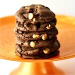 Stack of six chocolate peanut butter chip cookies on orange cake stand.