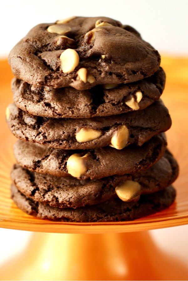 Stack of six chocolate peanut butter chip cookies on orange cake stand.