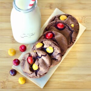 Five chocolate peanut butter cookies on napkin with peanut butter M&M's to the side.