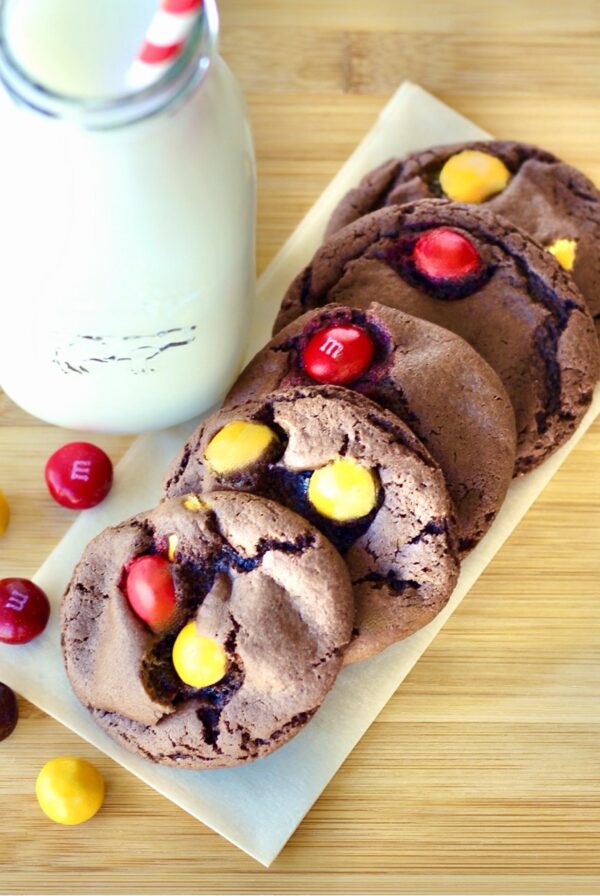 Five chocolate peanut butter cookies on napkin with peanut butter M&M's to the side.