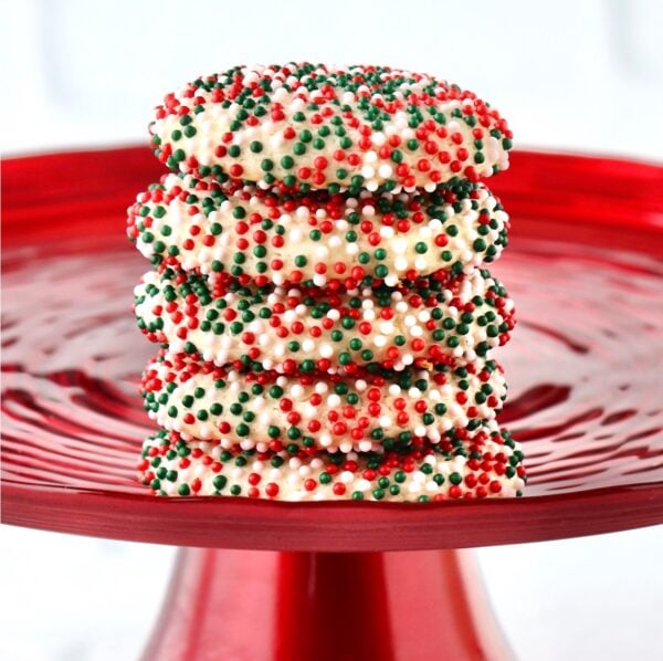 Stack of five sprinkle cookies on cake plate.