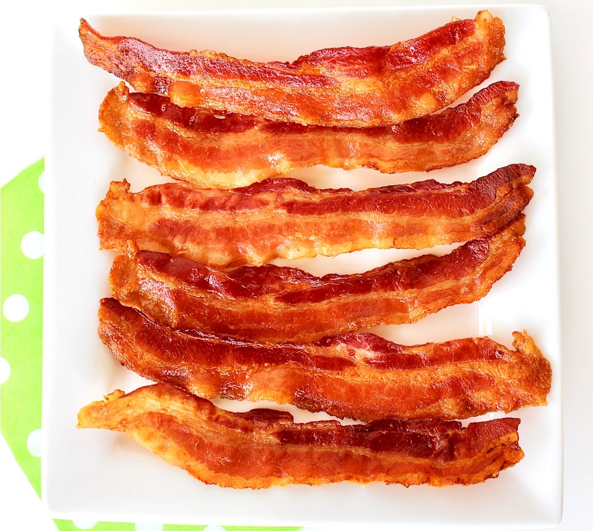 Six slices of cooked crispy bacon on plate.