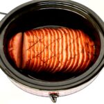 Sliced boneless ham in crock pot with maple brown sugar glaze.