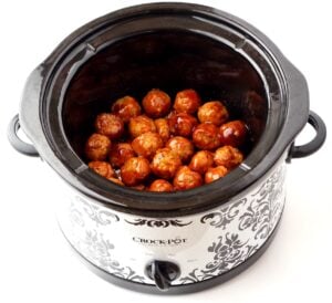 Cooked meatballs in crock pot glazed with honey garlic sauce.