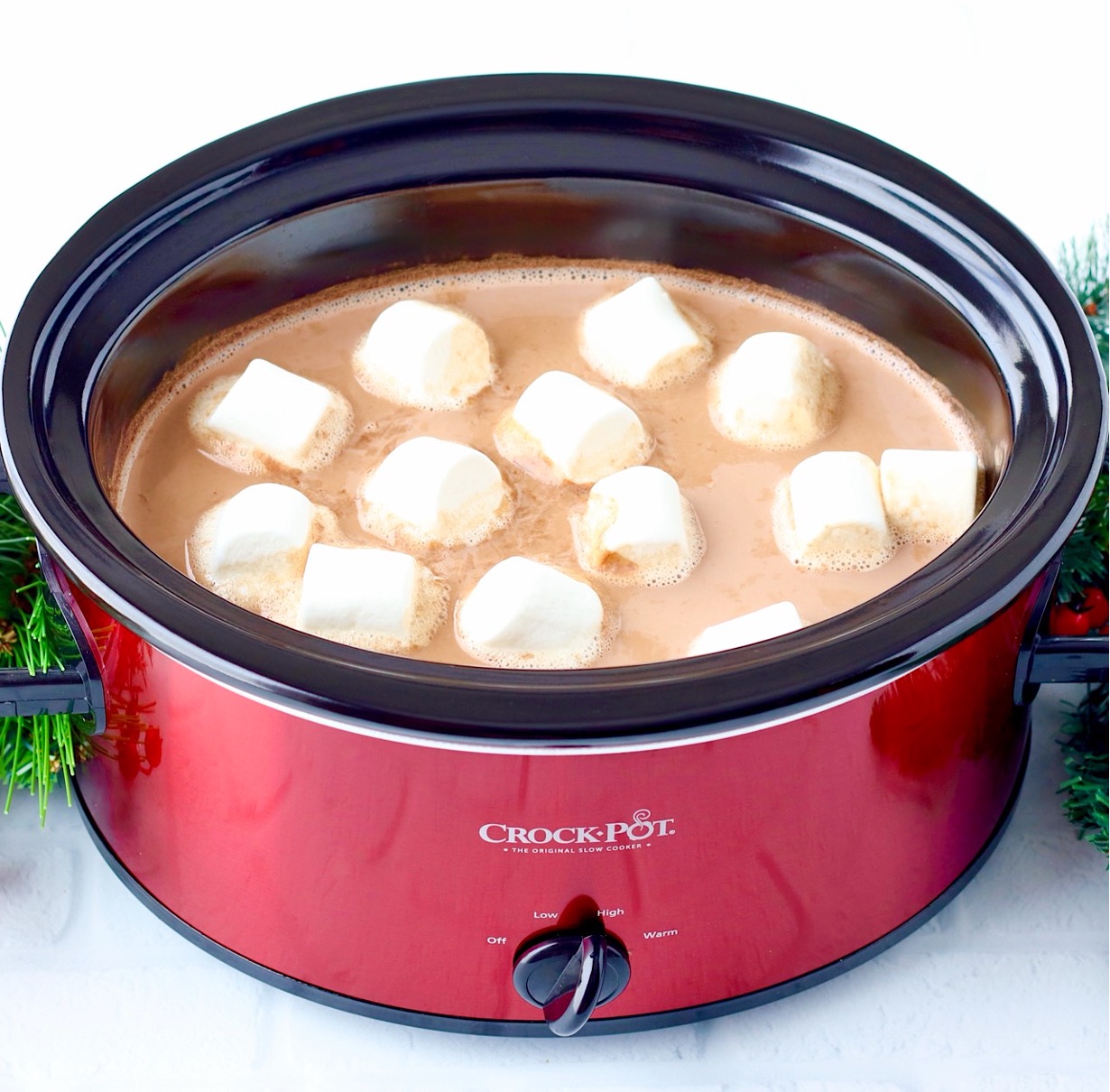Hot chocolate in crockpot with large marshmallows floating on top.