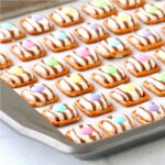 Easter pretzel treats with Hershey Hugs and spring M&M's on cookie sheet.